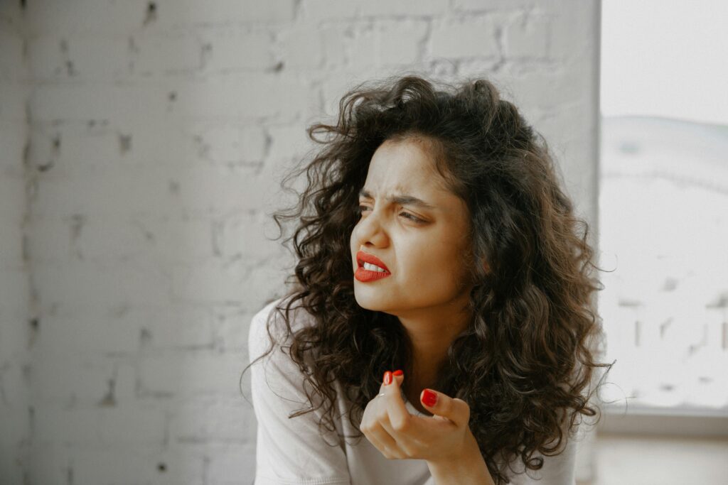 A woman with curly hair and a puzzled expression, reflecting confusion when identifying signs of a narcissistic mother.