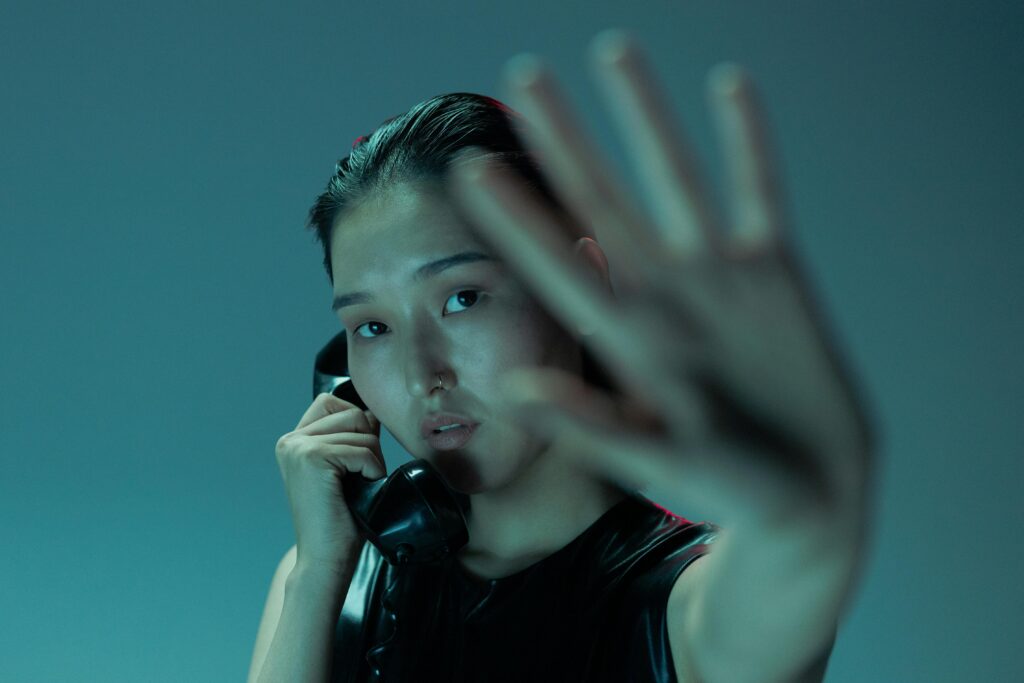 A woman holding a phone with her hand raised in a stop gesture, symbolizing healing from a narcissistic mother by going no contact.