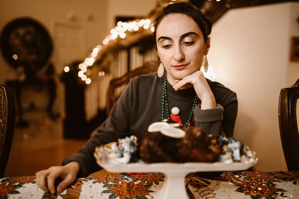 Woman sitting alone at a festive holiday table, symbolizing emotional challenges and stress tied to healing from a narcissistic mother during the holidays.