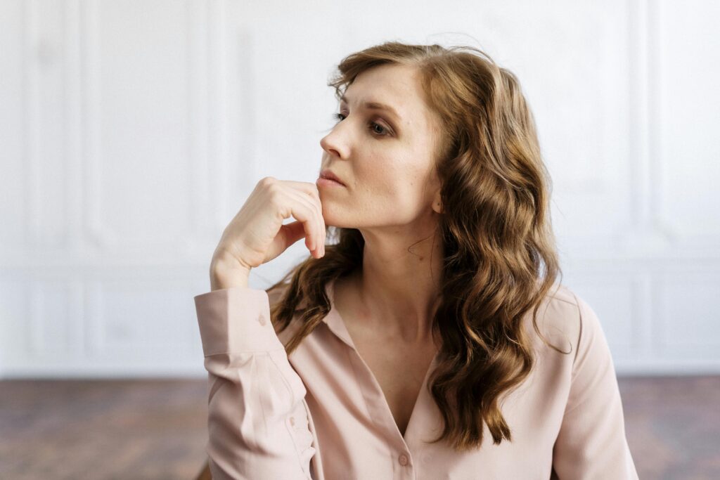 A thoughtful woman sitting and reflecting, symbolizing self-reflection and healing after going no contact with a narcissistic mother.