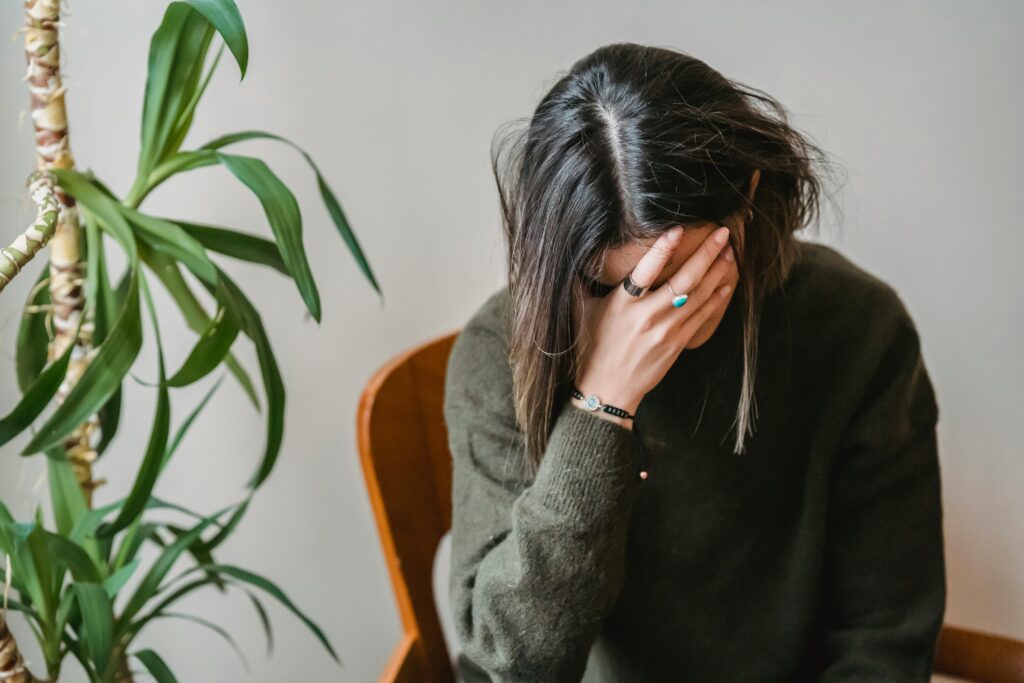 A woman sitting with her head down, representing emotional distress caused by criticism disguised as advice from a narcissistic mother.