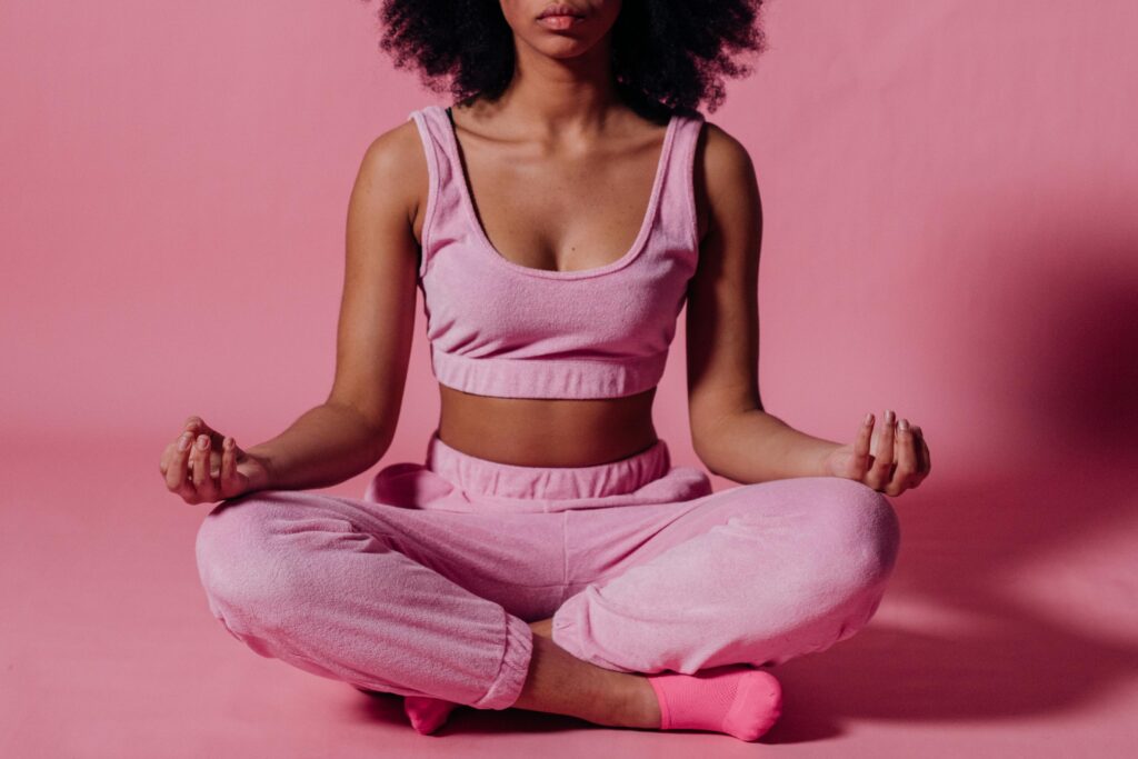 Woman sitting in a meditative pose wearing pink, symbolizing emotional resilience and balance after managing emotions with a narcissistic mother.