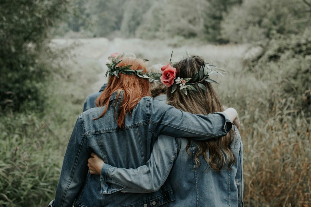 A group of women walking in nature with flower crowns and denim jackets, symbolizing support and healing from a narcissistic mother in the Empowered Daughter community.