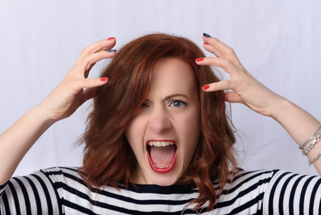 Woman screaming in frustration, symbolizing the emotional toll of managing emotions with a narcissistic mother.