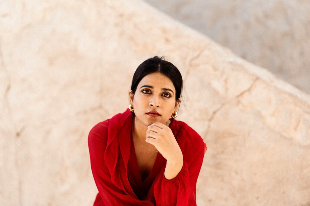 A woman in a red top sitting thoughtfully, symbolizing the introspection involved in realizing narcissistic abuse as an adult.