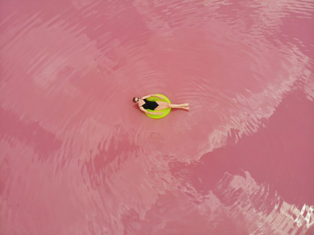 Woman floating calmly on a green pool ring in a pink lake, symbolizing the power of staying calm and managing emotions with a narcissistic mother.