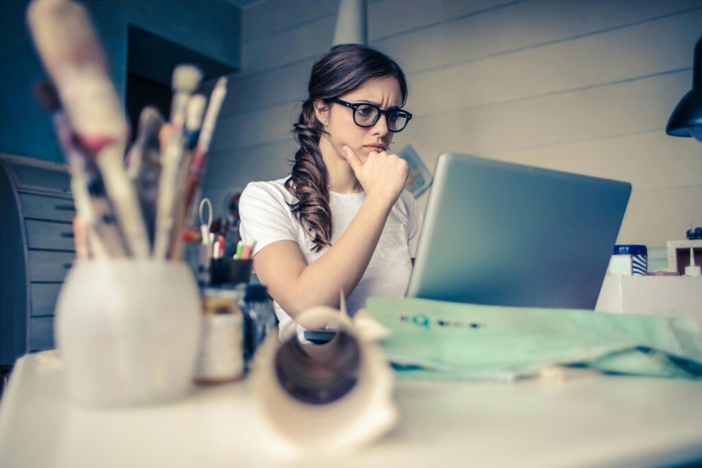 A woman wearing glasses sits at a desk, researching and reflecting on realizing narcissistic abuse as an adult.